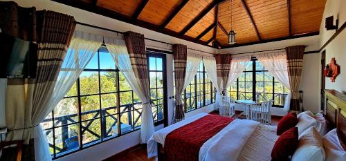 a bedroom with a bed and large windows at Chez Allen in Nuwara Eliya