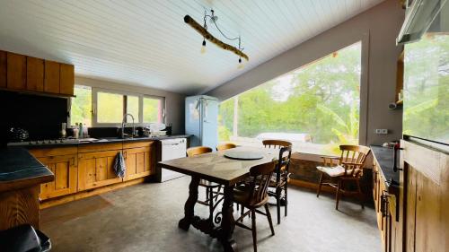 a kitchen with a table and chairs and a large window at Carwyns Surf House in Seignosse