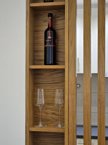 a bottle of wine in a cabinet with two wine glasses at Mimi in Vrnjačka Banja