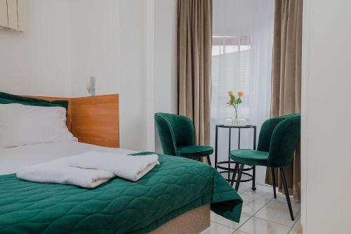 a bedroom with a bed and two green chairs at Zajazd Błonie in Błonie