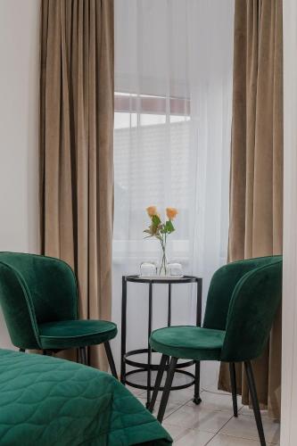 two green chairs and a table with a vase of flowers at Zajazd Błonie in Błonie