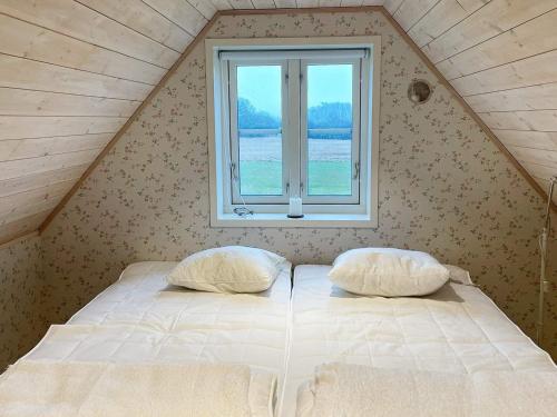 a bed with two pillows in a room with a window at Holiday home Löderup V in Löderup