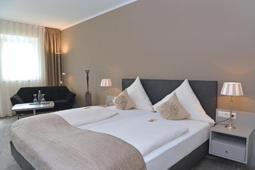 a hotel room with a large white bed and a chair at Landhotel Hauer in Pleisweiler-Oberhofen