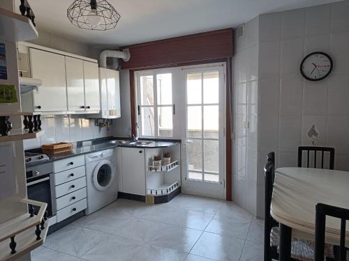 a kitchen with a washing machine and a window at Faro de Aldan in Aldán