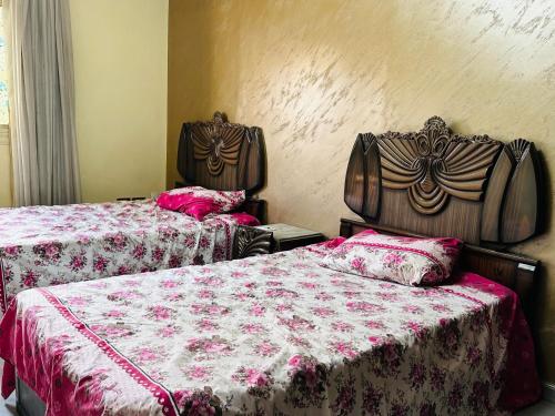 a bedroom with two beds with red and white sheets at 100برج الثورة الدور 2 in Cairo