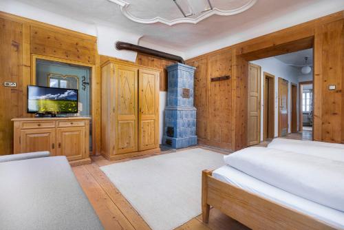 Gasthof Sillianer Wirt في سيليان: غرفة نوم بجدران خشبية ومدفأة وتلفزيون