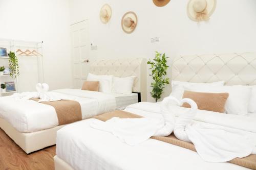 2 camas blancas en una habitación con paredes blancas en OHHSEM Hotel, en Semporna