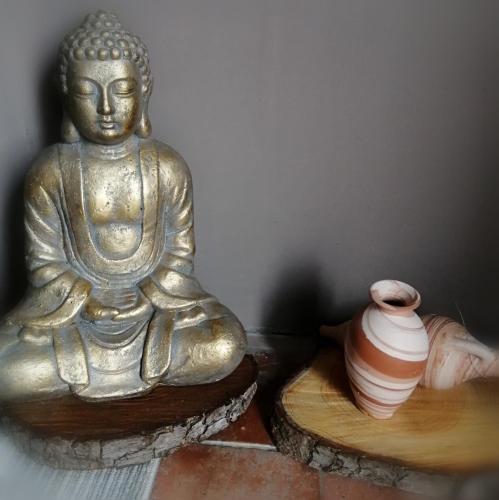 a statue of a buddha sitting next to a vase at Paradise Grand Jardin et Terrasse 2 chambres in Férolles