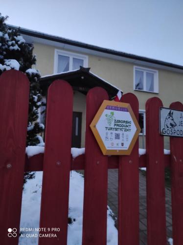 a sign on a red fence in front of a house at Dżolanda Pokoje in Milsko
