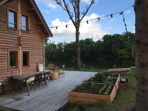 una terraza de madera con mesa de picnic y una casa en La cabane de l'étang en Feings