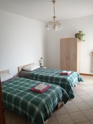 una camera con 2 letti e lenzuola verdi a quadri di 1000MigliaHouse a Brescia