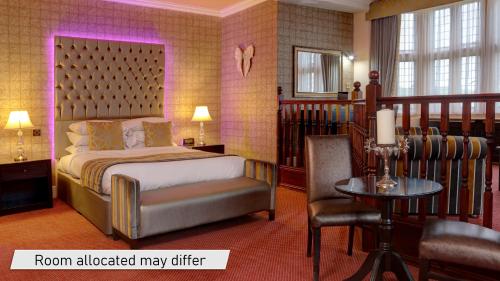 a bedroom with a bed and a chair and a table at Rogerthorpe Manor Hotel in Pontefract