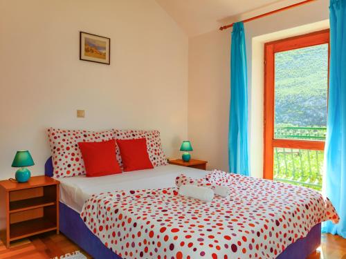 a bedroom with a red and white bed and a window at House Podaspilje Omis in Podšpilje