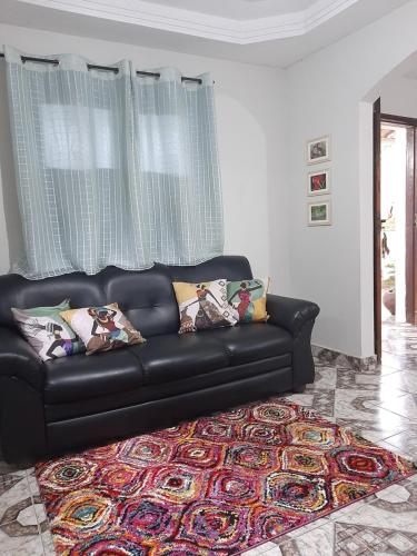 a black leather couch in a living room with a rug at Casa espaçosa com Wi-Fi, garagem para 2 veículos e área externa em Campos dos Goytacazes in Campos dos Goytacazes