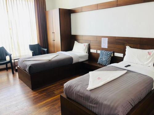 a hotel room with two beds and a desk at Belair Resorts in Kotagiri