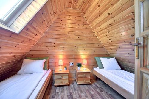2 Betten in einem Zimmer mit Holzwänden in der Unterkunft Houses with a garden- Domki z ogródkiem Radison domki in Mielno