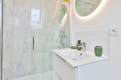 a white bathroom with a sink and a shower at Little Cosy - T2 avec parking in Vierzon