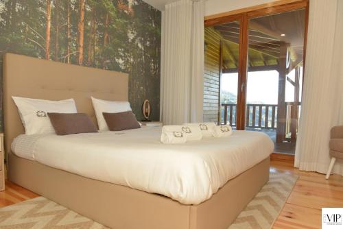 a bedroom with a large white bed with a large window at Casa da Moda - Turismo de Campo in Vieira do Minho