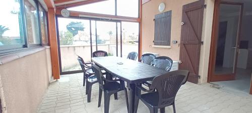 une table et des chaises en bois sur une terrasse dans l'établissement Patios de la mer Villa à 200 m de la plage- Clim - Wifi - parking, à Saint-Cyprien