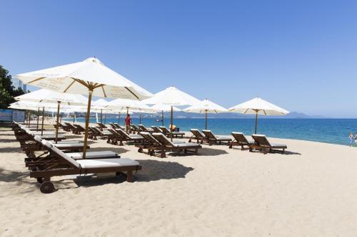 a row of chairs and umbrellas on a beach at Regalia Nha Trang in Nha Trang
