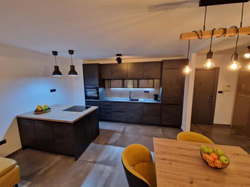 a kitchen with wooden cabinets and a table with a bowl of fruit at Apartment Matea in Pula