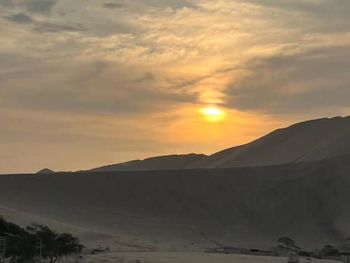 una puesta de sol en el desierto con montañas en el fondo en Ica tierra del sol eterno 2, en Ica