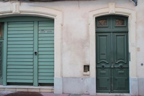 2 portes vertes sur le côté d'un bâtiment dans l'établissement La Casa De Planel, à Montpellier