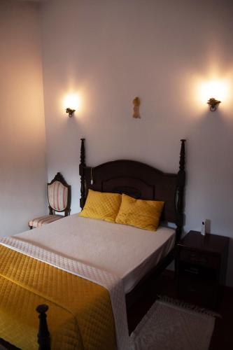 a bedroom with a bed with yellow pillows and a chair at Casa Senhor da Ponte in Mondim de Basto