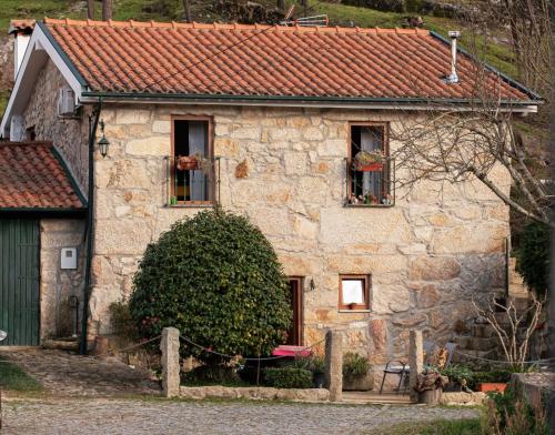a stone house with two windows and a roof at Casa Senhor da Ponte in Mondim de Basto