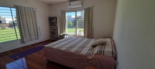 ein Schlafzimmer mit einem Bett und einem großen Fenster in der Unterkunft Hermosa Casa Quinta en Junin in Junín