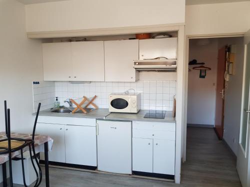 a kitchen with white cabinets and a microwave at Le studio 19 in Saint-Cast-le-Guildo