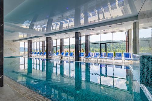 una gran piscina con sillas azules en un edificio en Elena Spa Resort, en Bukovel