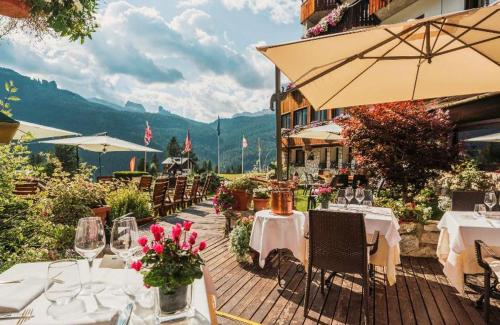 コルティーナ・ダンペッツォにあるホテル ミラージュのテーブルと椅子、傘が備わるレストラン