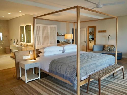 a bedroom with a large canopy bed and a bathroom at Sala Beach House in Ballito