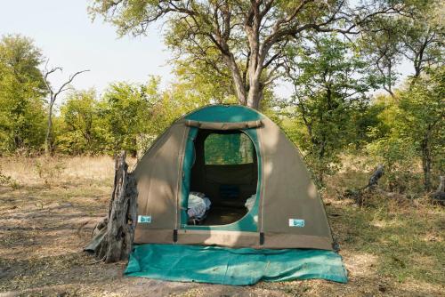 a tent in a field next to a tree at Nahubwe Safari Lodge in Ngoma