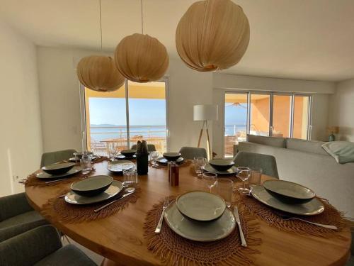 une table en bois avec des assiettes et des verres au-dessus dans l'établissement Paillote Perchée à 180 ° sur la mer, à Ajaccio