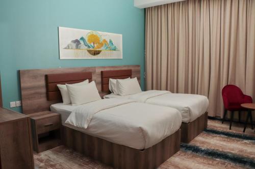 a hotel room with two beds and a desk at Ewann Hotel Apartments in Nizwa