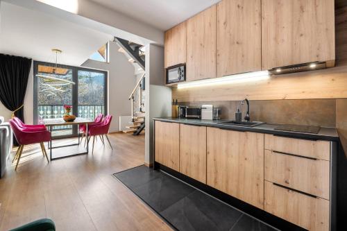 a kitchen with wooden cabinets and a table with pink chairs at Rezydencja Strążyska & Chalet BBQ in Zakopane