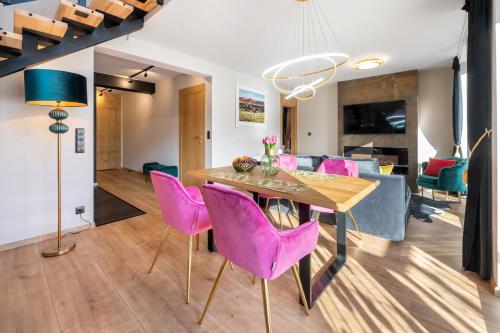 a dining room and living room with pink chairs and a table at Rezydencja Strążyska & Chalet BBQ in Zakopane