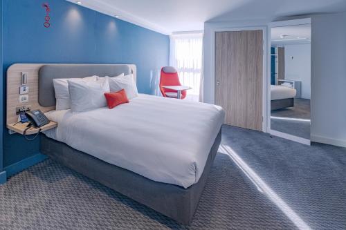 a bedroom with a large bed and a red chair at Holiday Inn Express - Fleet by IHG in Fleet