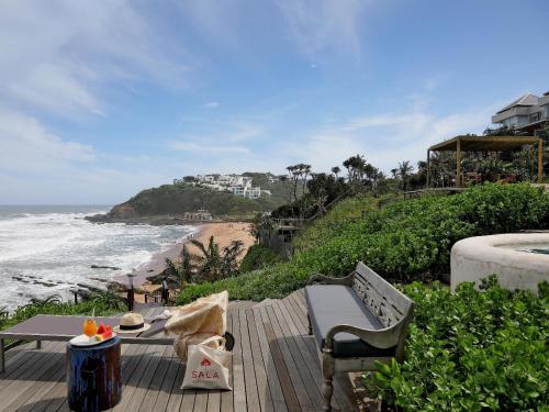 a wooden deck with a table and chairs and the beach at Sala Beach House in Ballito