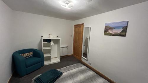 een woonkamer met een blauwe stoel en een koelkast bij 36 Westview Terrace in Stornoway