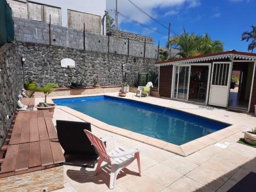 a swimming pool in front of a stone building with a chair at La case d'Isabelle in Saint-Denis