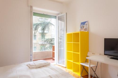 une chambre avec un mur jaune et une télévision dans l'établissement BnButler - Casa Lario - Isola District, à Milan