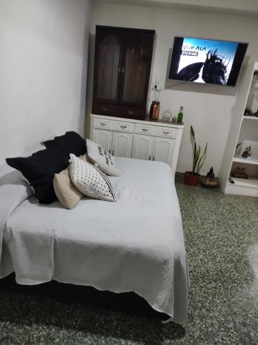 a bedroom with a white bed with a flat screen tv at Casa Isa in Ezeiza