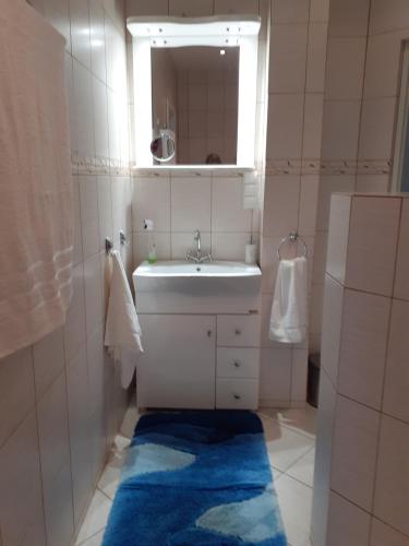 a bathroom with a sink and a mirror and a blue rug at Appartment Bawaria in Cieszyn
