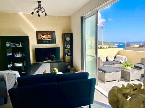 a living room with a blue couch and a large window at Ta Phyllis - Apartments & Villas with Sunset & Sea Views in Għajnsielem
