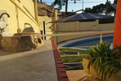 a house with a swimming pool and an umbrella at Casa con vistas al mar in Castelldefels