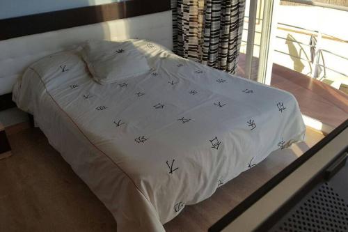 a bed with a white comforter with birds on it at Casa con vistas al mar in Castelldefels