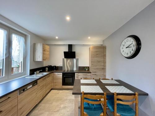 une cuisine avec une table et une horloge au mur dans l'établissement ❊ AU MURMURE DE L'EAU AU COEUR DE L'ALSACE ❊, à Ebersheim